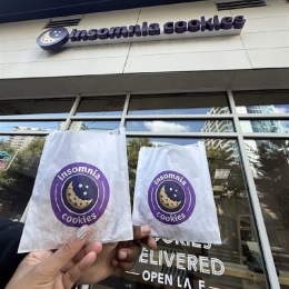 a person holding cookies in front of a store